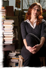 Jenevive Desroches sitting next to a stack of books